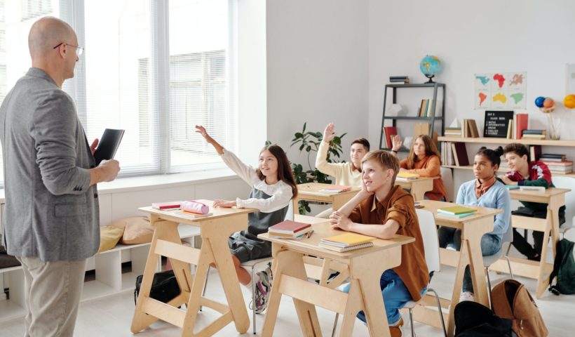 students raising their hands in the classroom
